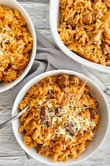 Greek lamb and tomato stew in a white bowl with orzo pasta- Kritharaki- Yiouvetsi