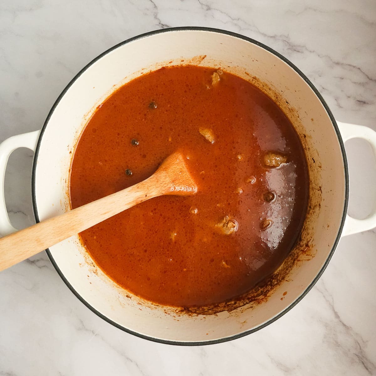 Greek lamb and tomato stew sauteing diced lamb in pot and adding tomato passata and stock