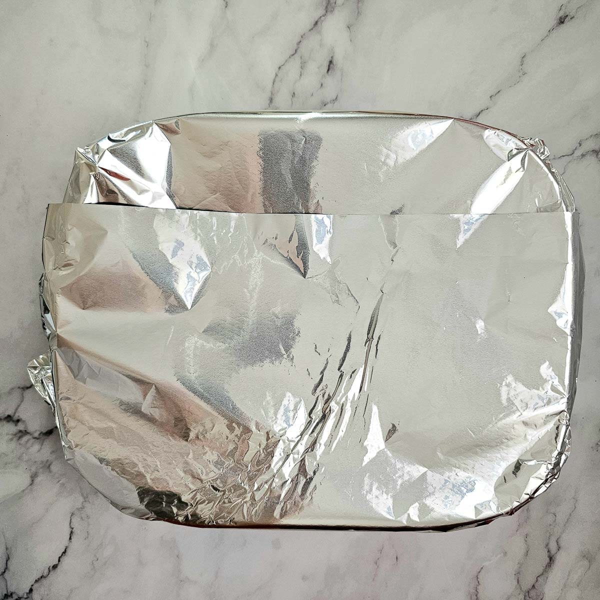 Greek lamb and tomato stew baking dish covered with foil