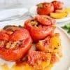 Greek stuffed tomatoes with rice- Yemista, on a white plate with some baked potatoes.