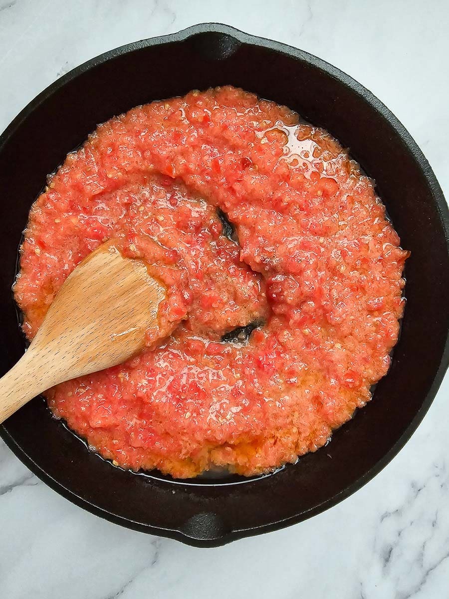 adding tomato paste in a pan for Strapadsada-Greek scrambled eggs and tomatoes.