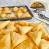 Greek cheese triangles-tiropitakia on a plate ready to serve and baking tray in background