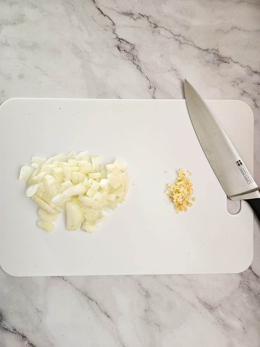 diced onion and chopped garlic on chopping board