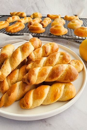 Greek Easter cookies-koulourakia on white plate and cooling rack.