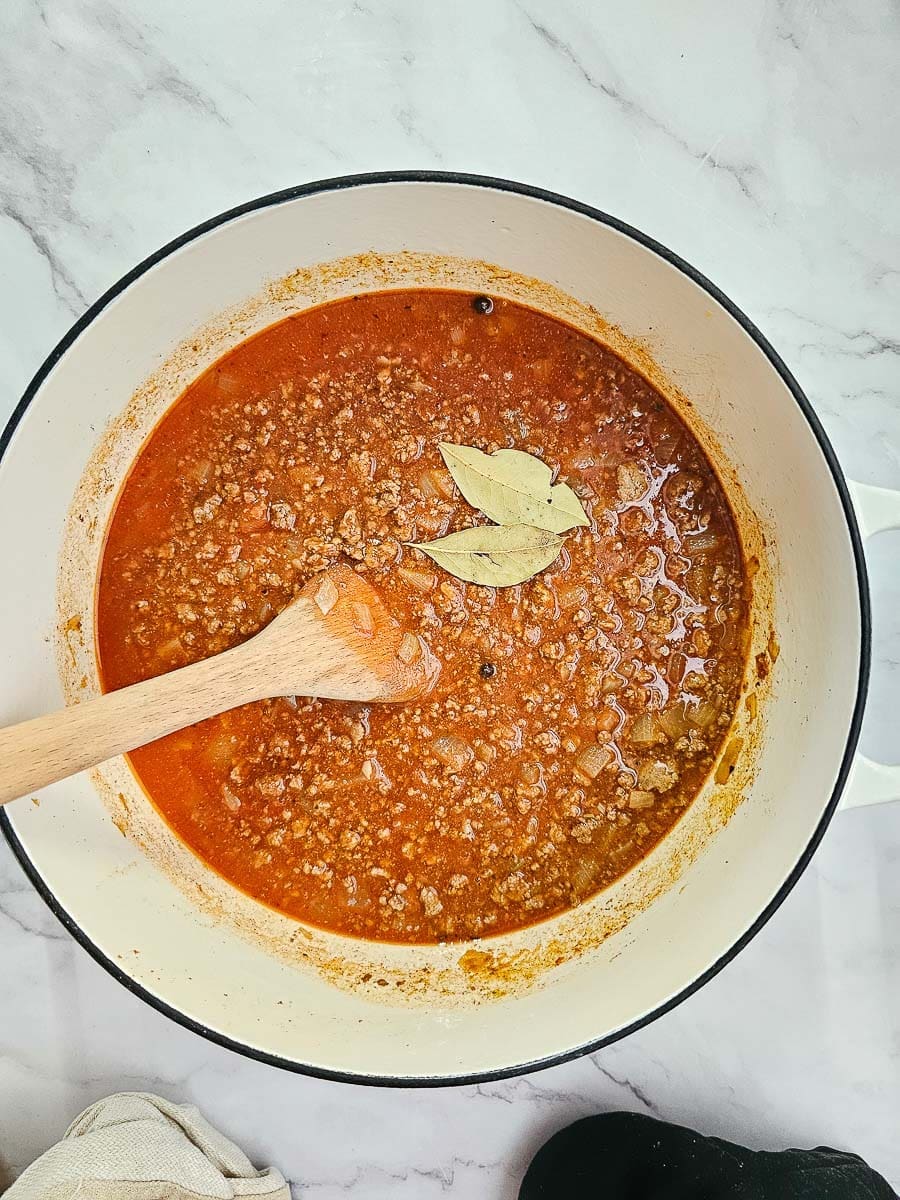 Greek pasta bake-pastitsio, add tomato puree and bay leaves