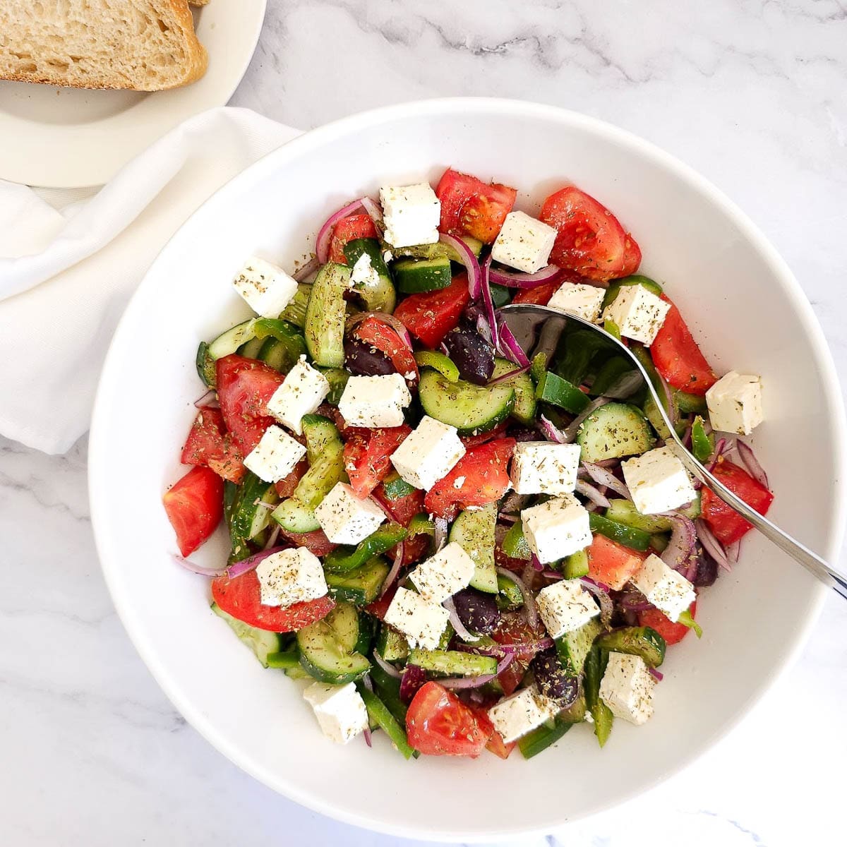 Greek salad with cucumbers, tomatoes, feta cheese and olives in a bowl.