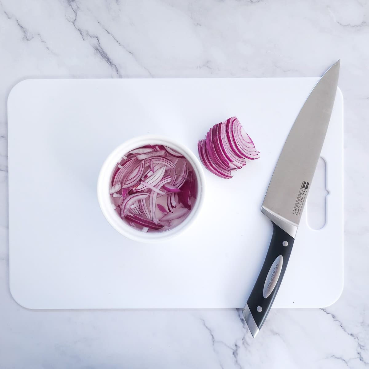 Greek salad-sliced red onions on chopping board with knife