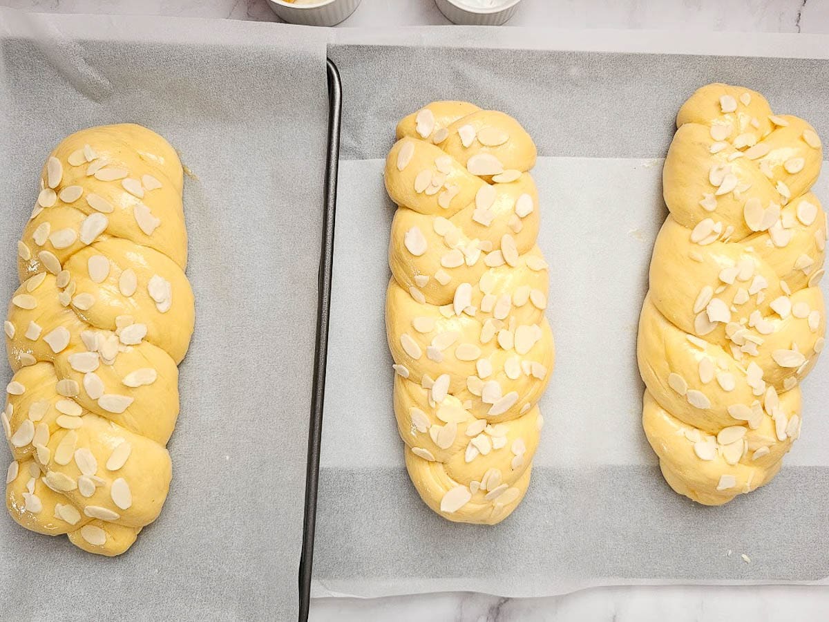 tsourekia uncooked on baking tray with flaked almonds