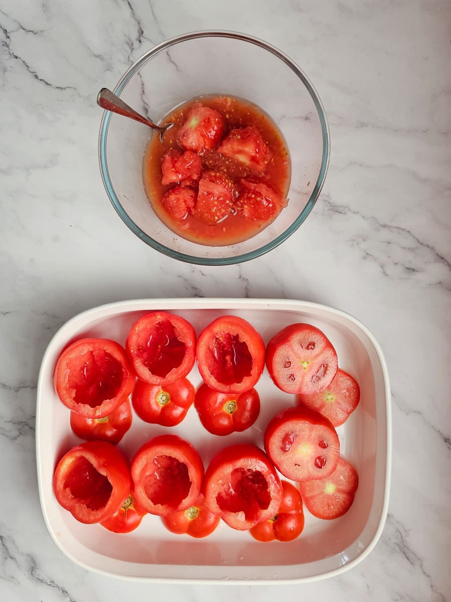 Yemista, stuffed tomatoes with rice in a baking tray with flesh spooned out.