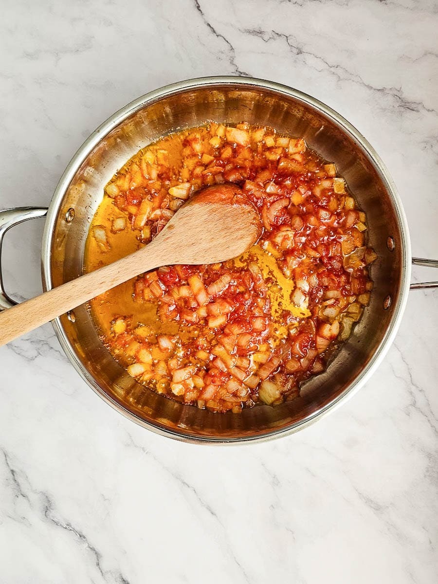 Yemista, stuffed tomatoes with rice, saute onions and tomato paste in pan. 