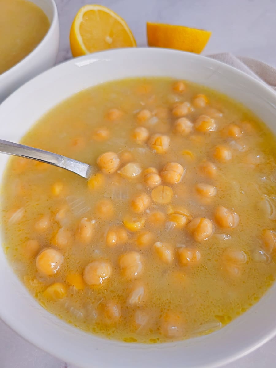 chickpea soup in a white bowl with lemon