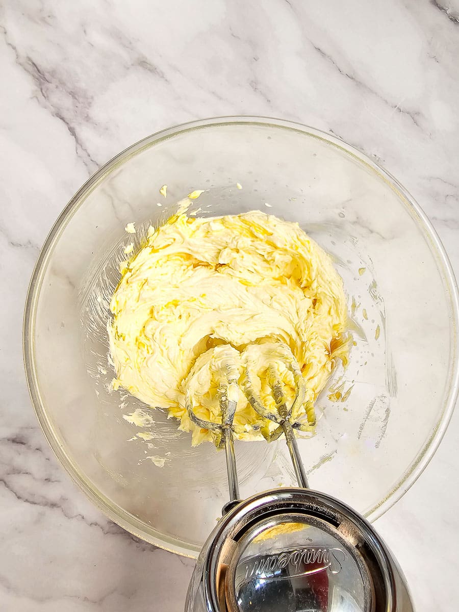 creaming butter and sugar in bowl and adding vanilla and egg yolk