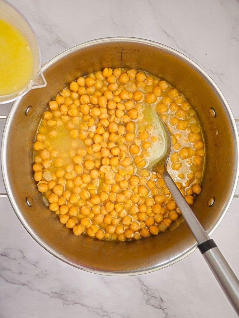 adding broth to pot with chickpeas