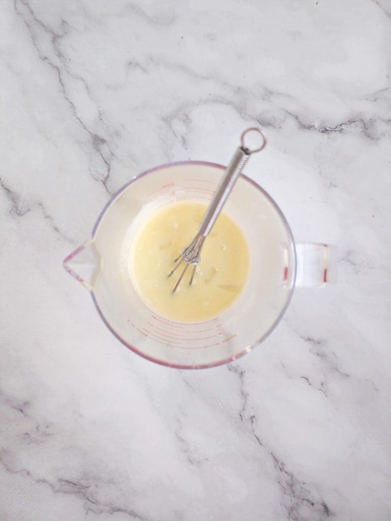 flour and water with whisk in measuring jug