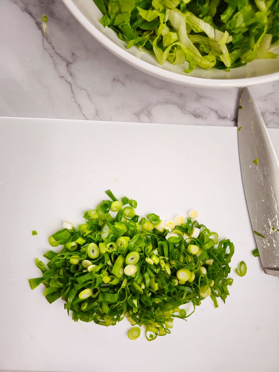 finely sliced spring onions on a chopping board