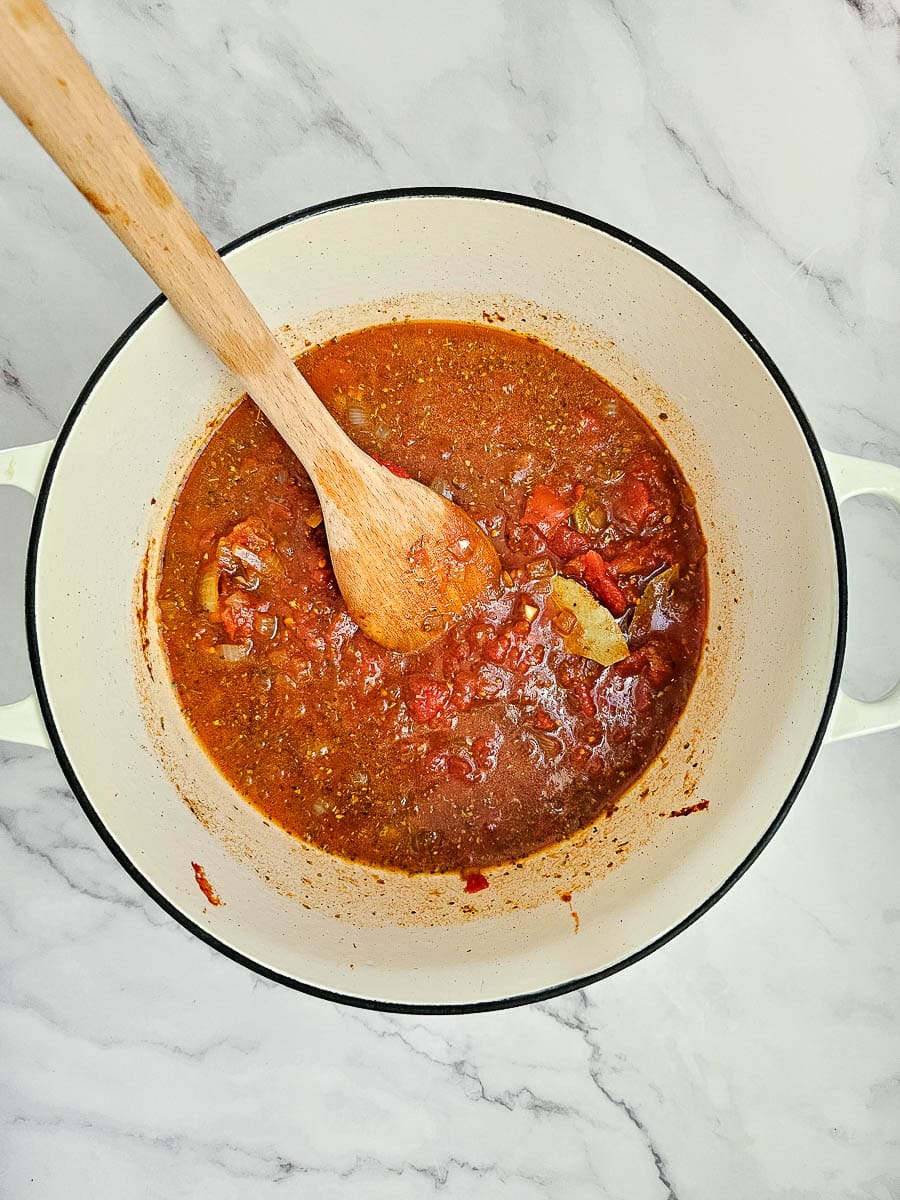 sauteing onions and garlic in pot with a wooden spoon and adding tomato suace