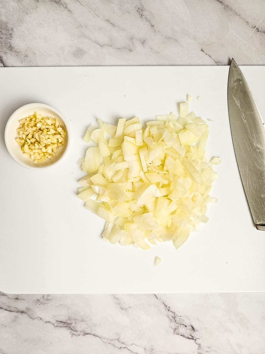 Sliced onions and crushed garlic on a chopping board