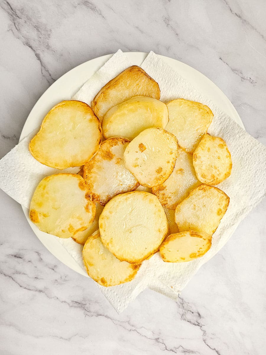 sliced shallow fried potatoes on plate with paper towel