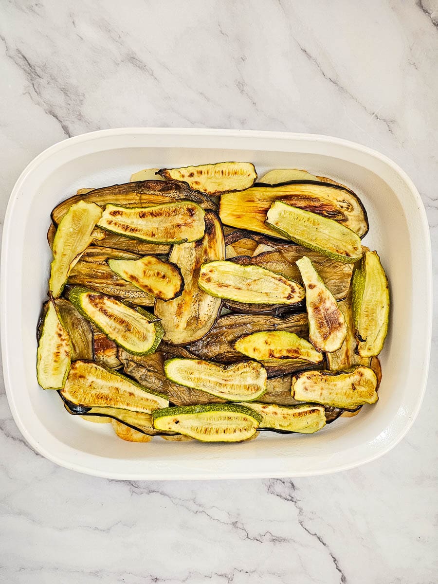 layered potatoes ,eggplant and zucchini in a baking dish for vegan moussaka