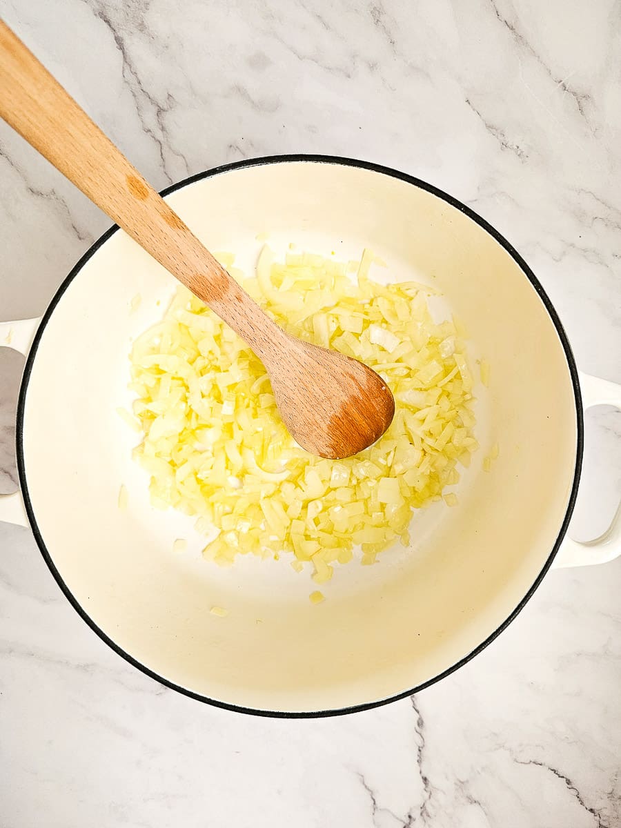 sauteing onions and garlic in pot with a wooden spoon