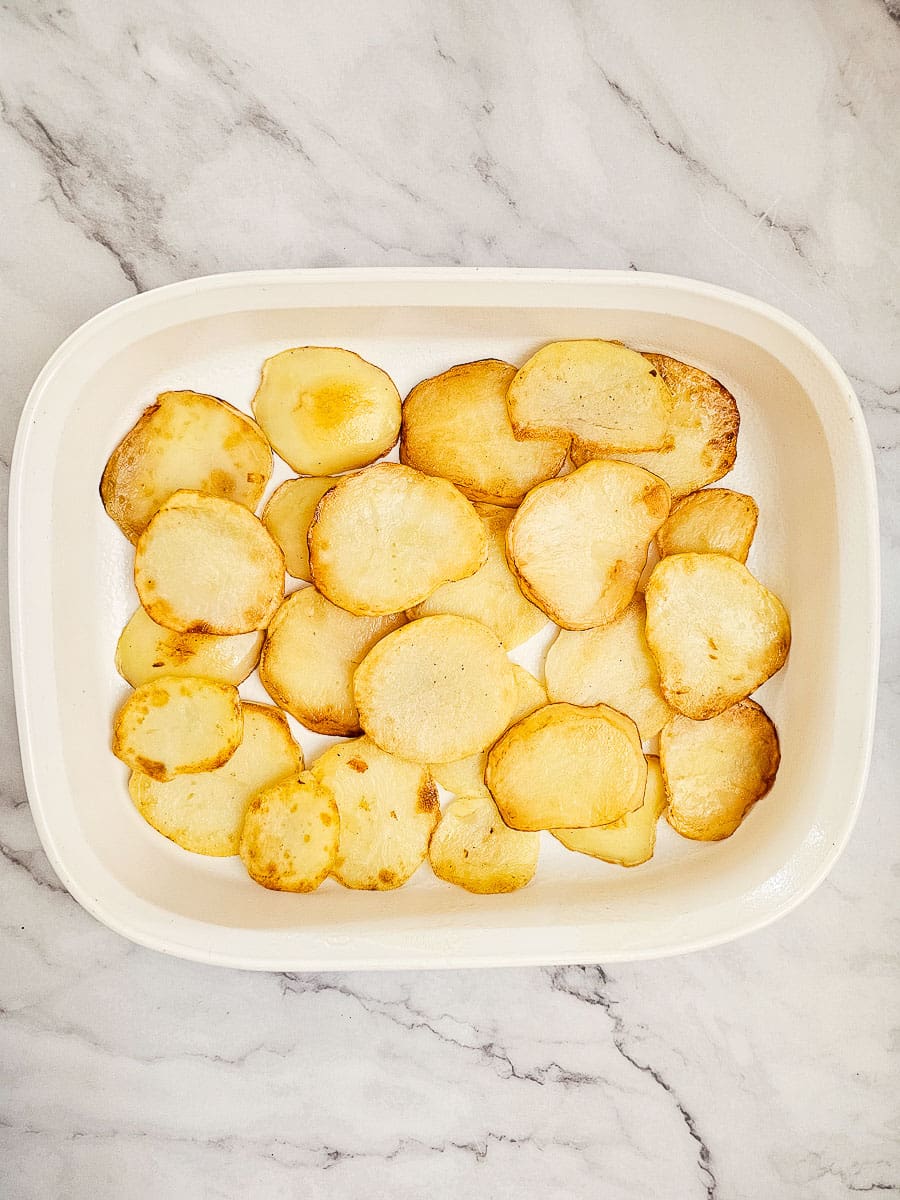 Layered potatoes in a baking dish for vegan moussaka