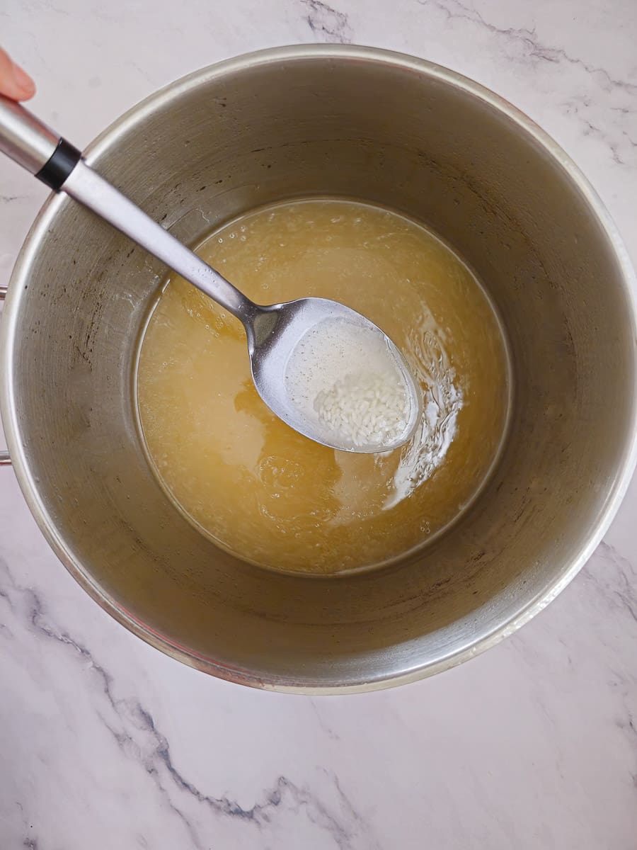 adding rice to chicken broth in a large pot for soup