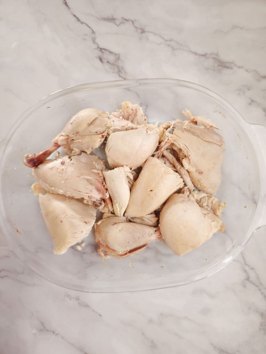 boiled chicken in a baking dish cut into smaller pieces