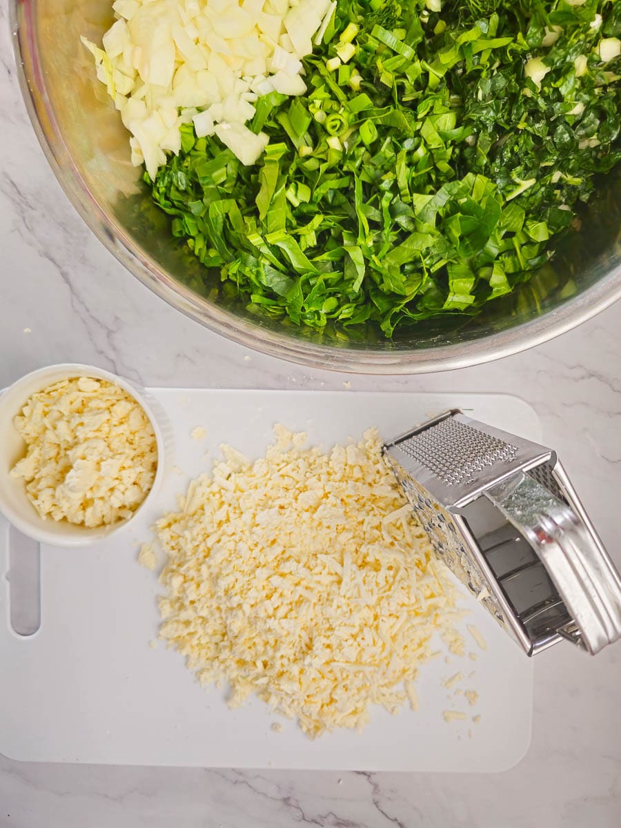 Grate feta cheese for spanakopita