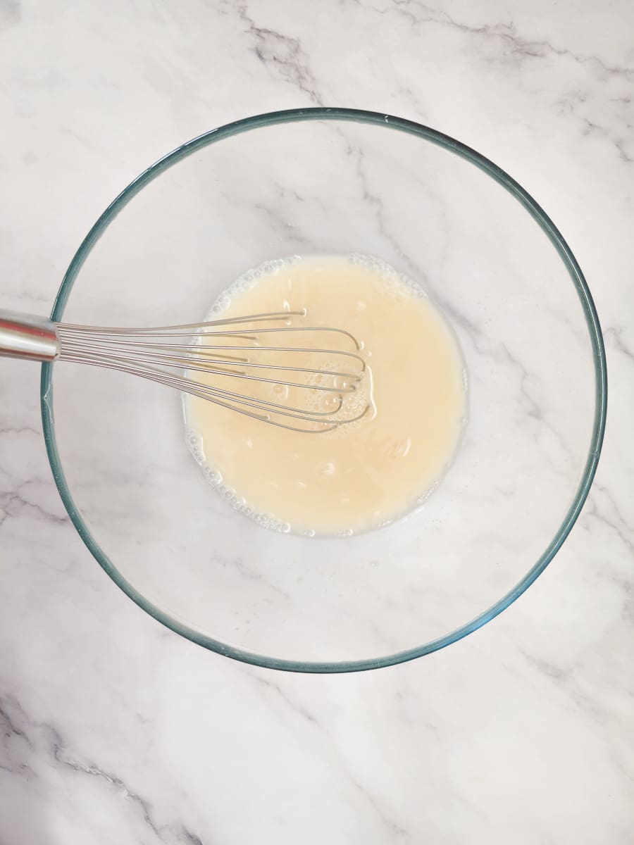 whisking yeast, water and sugar in a glass bowl