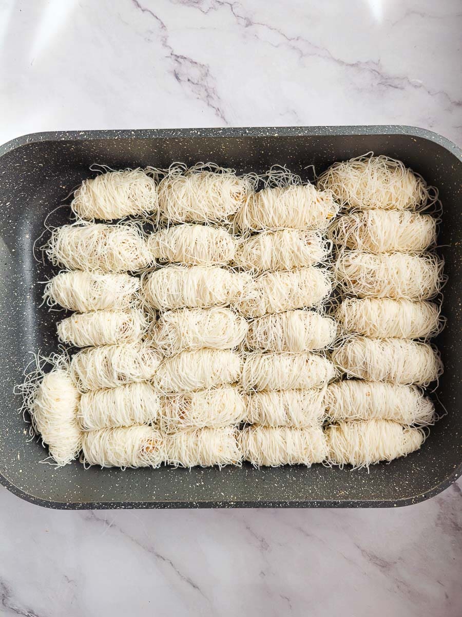 Rolling Kataifi - Greek String Pastry Nut Rolls in bakingdish before baking