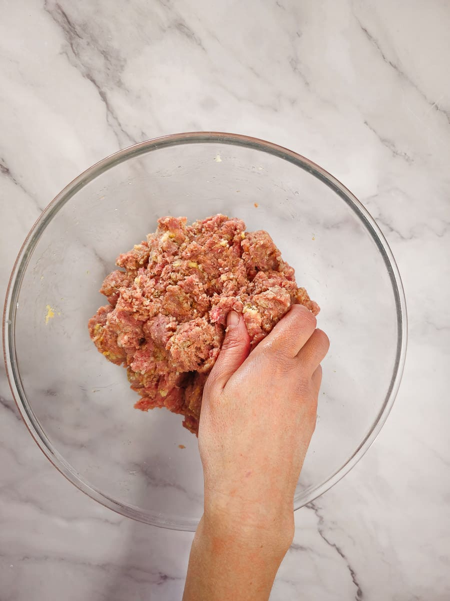 mixing mince mixture in a bowl with hands