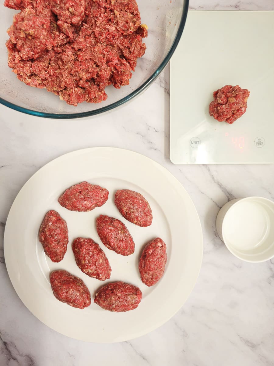 Shaped Soutzoukakia - Greek meatballs on a plate and portioning