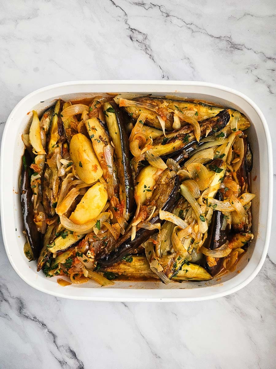 eggplant, potato and tomato casserole in baking dish before baking