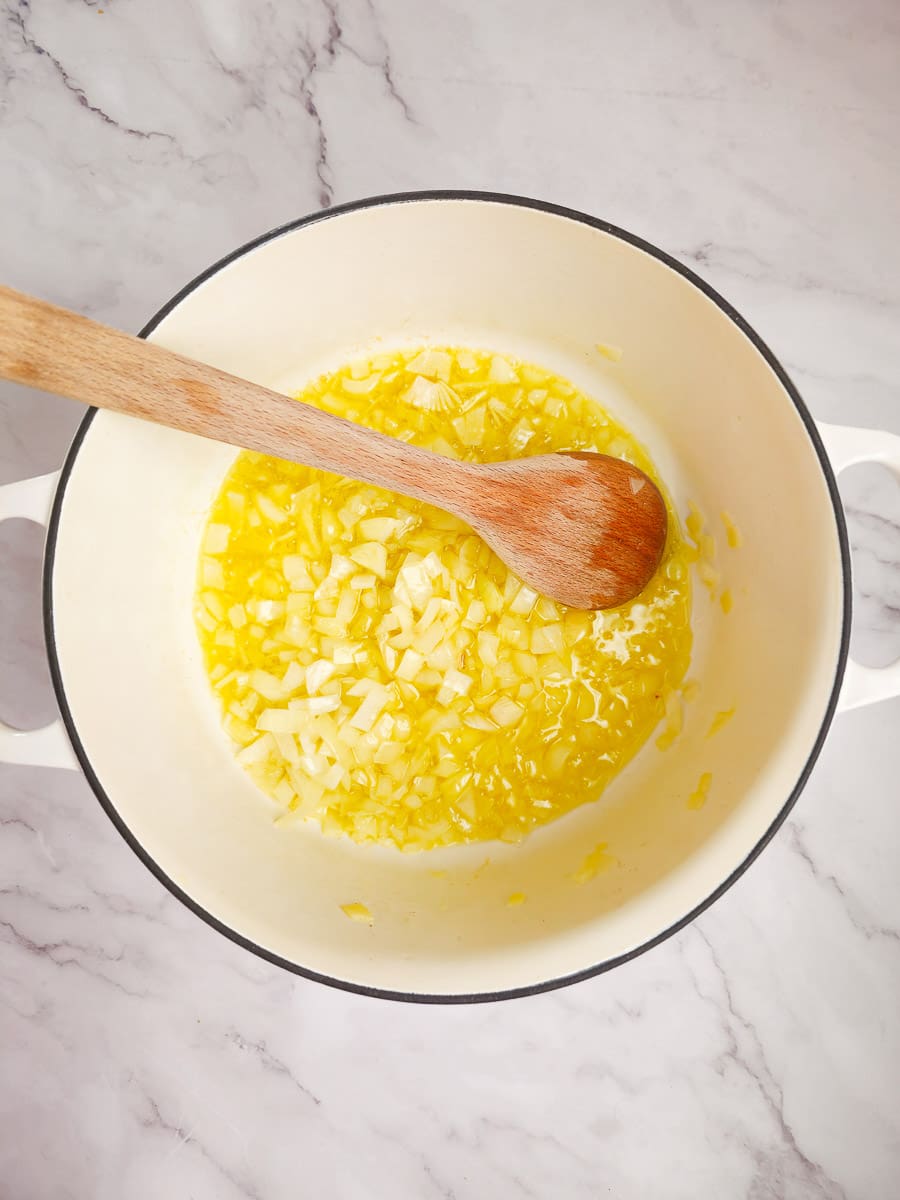 sauteing onions in pot with wooden spoon