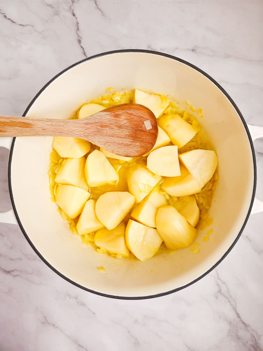 sauteing potatoes in pot with wooden spoon