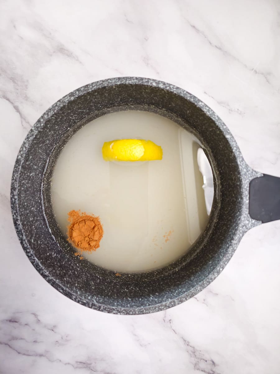 sugar syrup in saucepan with lemon and cinnamon