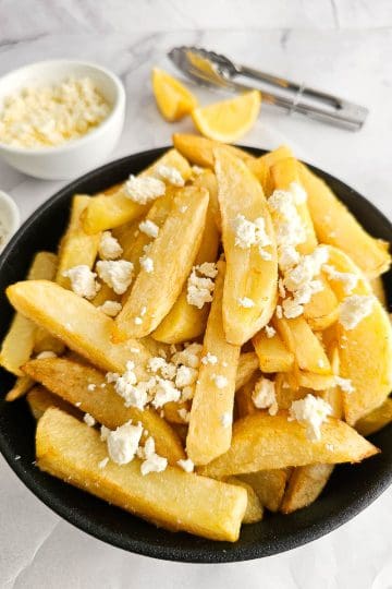 Greek Olive Oil Fries - Patates Tiganites, in a bowl with crumbled feta