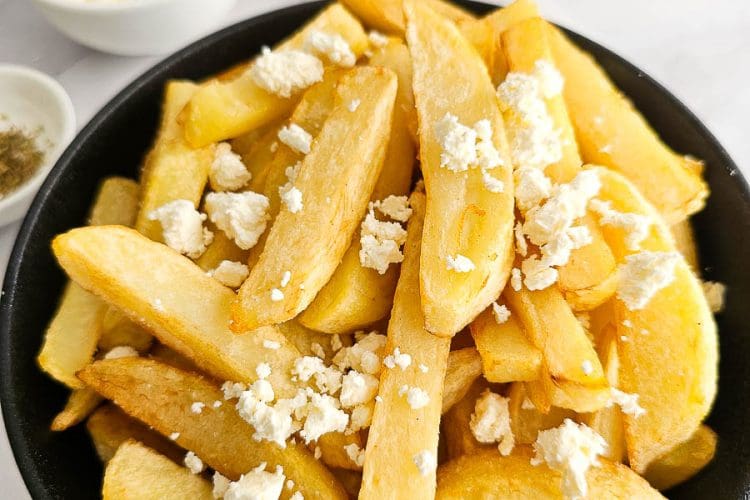 Greek Olive Oil Fries - Patates Tiganites, in a bowl with crumbled feta