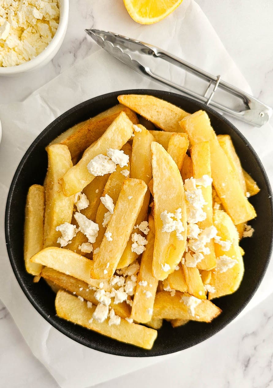 Greek Olive Oil Fries - Patates Tiganites in a bowl with crumbled feta