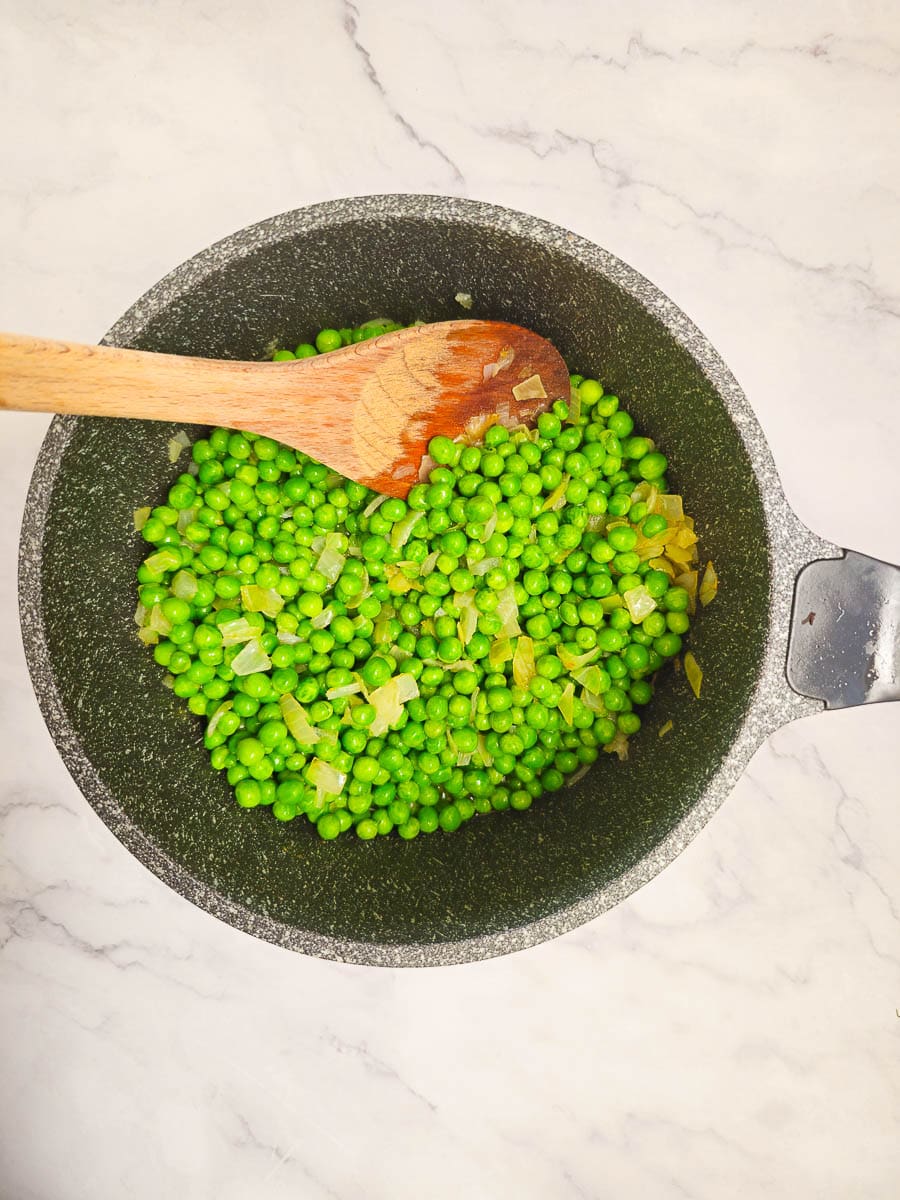 Greek Peas in Tomato Sauce, Arakas Latheros simmering in a pot with a wooden spoon. 