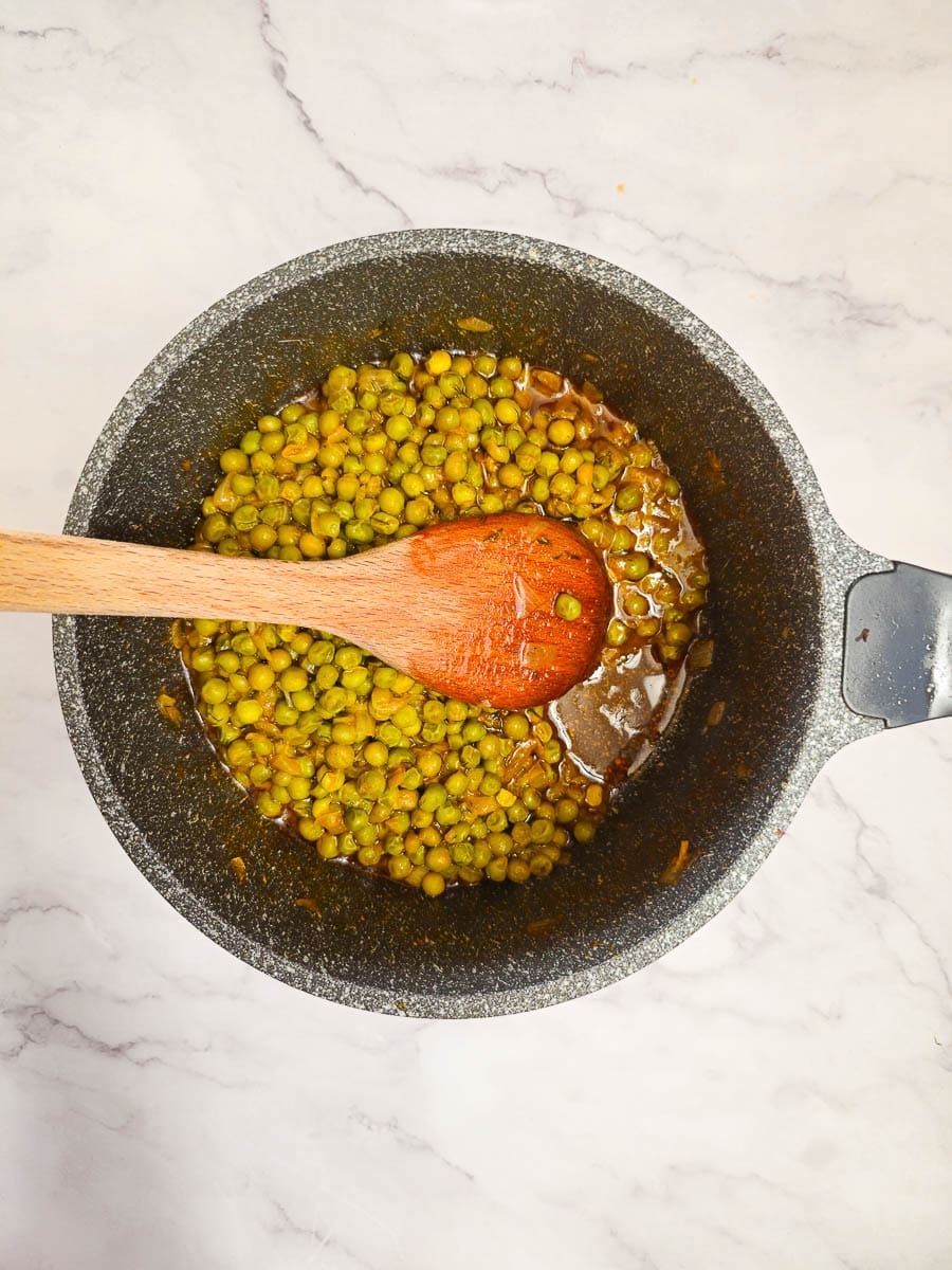 Greek Peas in Tomato Sauce (Arakas Latheros) in a pot with a wooden spoon.