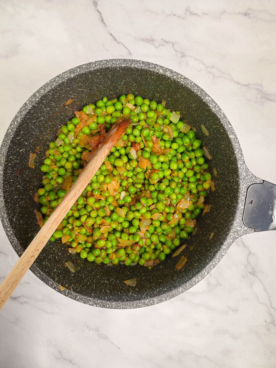 Greek Peas in Tomato Sauce, Arakas Latheros simmering in a pot with a wooden spoon. 