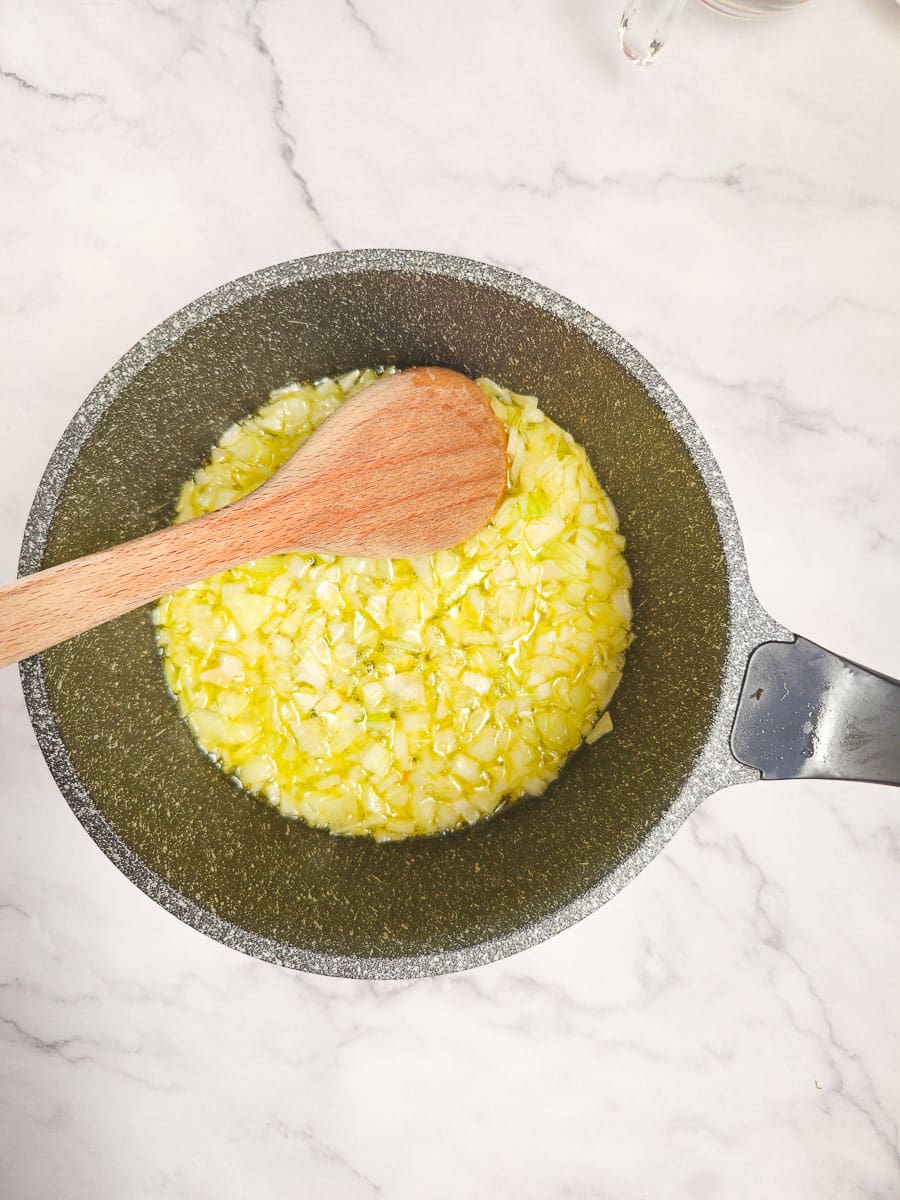 sauteing onions in a pot with a wooden spoon