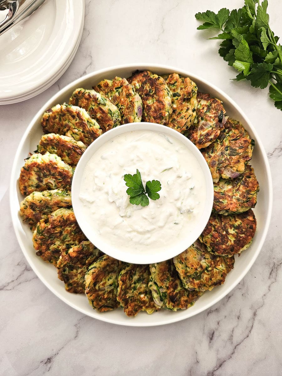 Greek Zucchini Fritters - Kolokithokeftedes on a plate with tzatziki