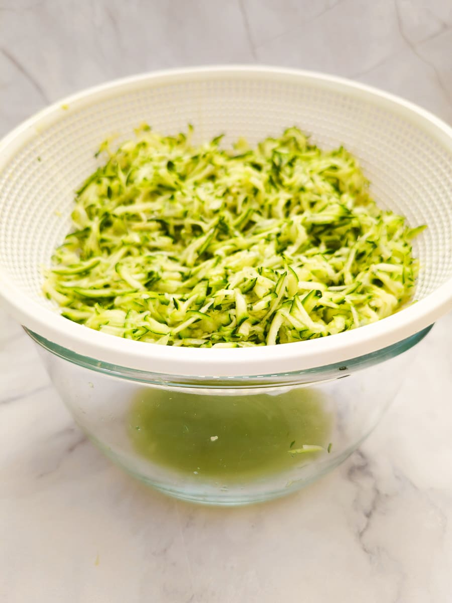 Straining grated zucchini in colander