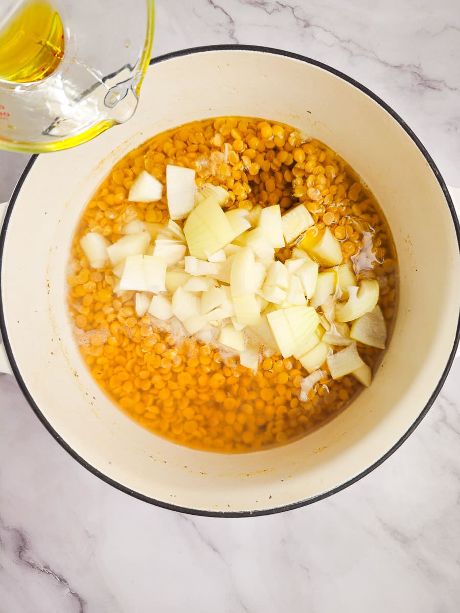 adding onions to fava- yellow split pea puree in pot