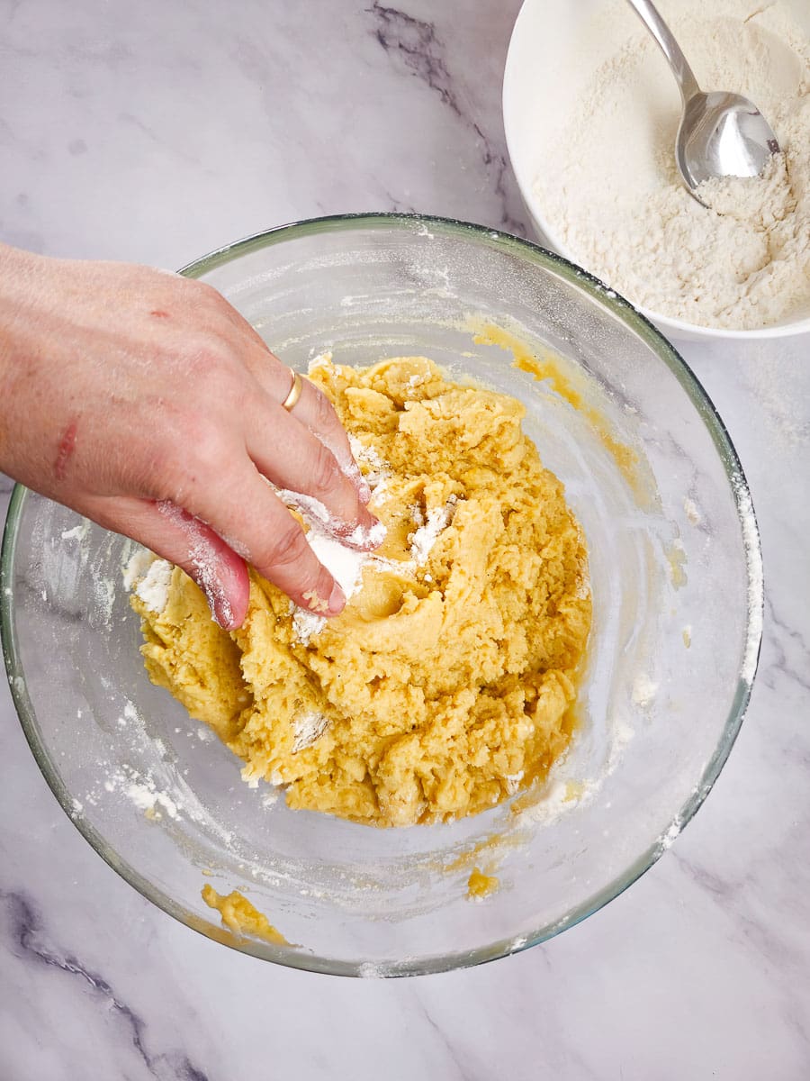 Melomakarona - Greek Honey Cookies mixing dough in bowl by hand.