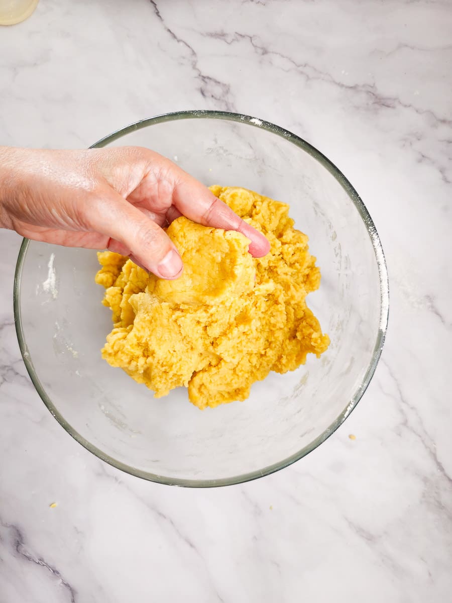 Melomakarona - Greek Honey Cookies mixing dough in bowl by hand.