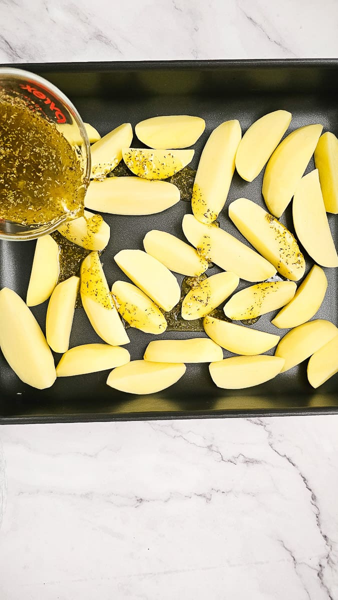 Adding marinade to Greek Lemon Potatoes in baking dish