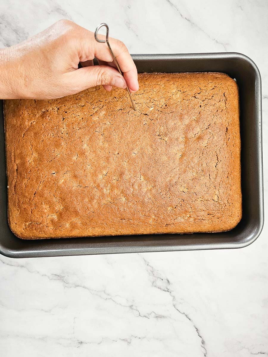 Karidopita - Greek Walnut Cake in baking tray poking holes